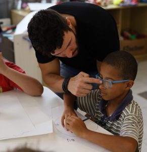 André Baia ajusta o óculos de um garoto que participa do workshop.
