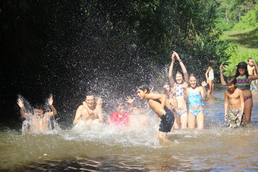 crianças brincando em uma lagoa, jogando água para cima