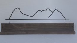 prateleira de madeira, com a silhueta das montanhas chamadas Mulher de Pedra, feitas em aço.