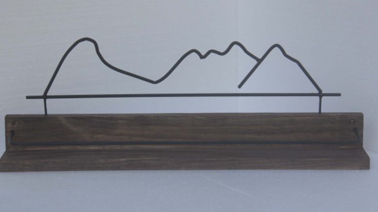 prateleira de madeira, com a silhueta das montanhas chamadas Mulher de Pedra, feitas em aço.