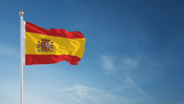 Imagem da bandeira da espanha tremulando em um mastro, com o céu azul.