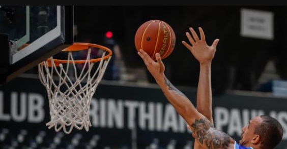 imgem mostra apenas as mãos de jogadores disputando uma bola de basquete ao lado da cesta.