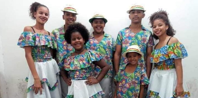imagem de um conjunto de cinco jovens e três crianças, com roupas em tecido florido. todos posam para a câmera.