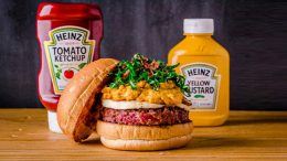 Imagem de hamburguer alto, com um pote de catchup e outro de mostarda atrás, anunciando o Burger Fest