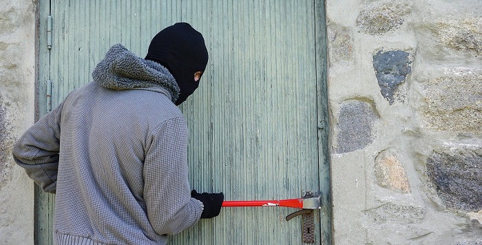 cena violência contra patrimônio: pessoa tenta abrir uma porta a força com uma barra de ferro