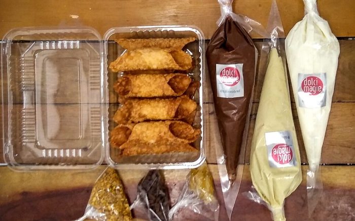 imagem do kit cannoli, uma das sugestões de sabores italianos para as festas: em uma embalagem os rolinhos de massa, três bisnagas com recheios e três saquinhos de castanhas
