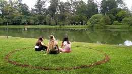 imagem de três moças sentadas dentro de um circulo demarcado no gramado, a novidade do ibirapuera para garantir distanciamento