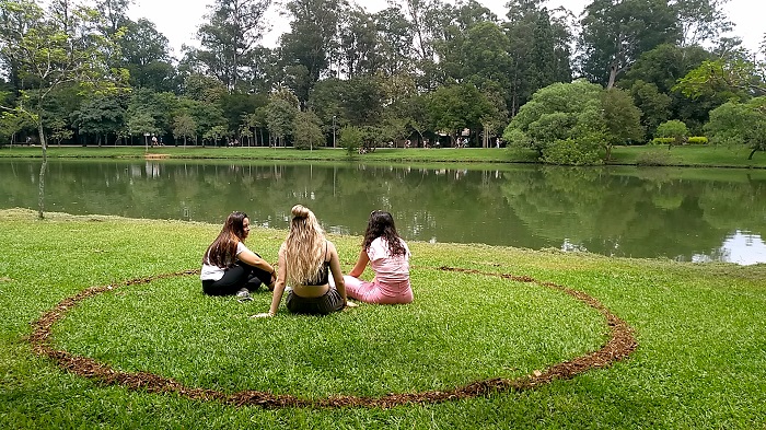 imagem de três moças sentadas dentro de um circulo demarcado no gramado, a novidade do ibirapuera para garantir distanciamento