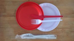 imagem de produtos vetados pela lei dos plásticos: pratinhos e talheres nas cores branco e vermelho, feitos de plastico descartável.