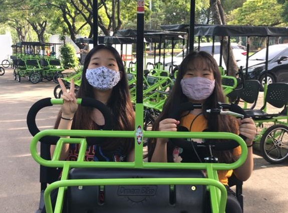 duas crianças de máscara em um quadriciclo. 