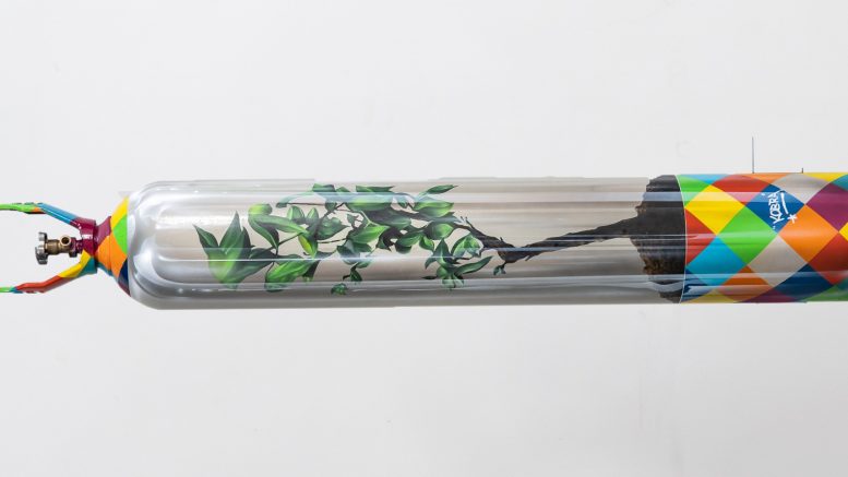 cilindro de oxigenio pintado por Eduardo Kobra, na horizontal, a pintura dá a impressão de um recipinente transparence com uma pequena arvore plntada na terra dentro dele.