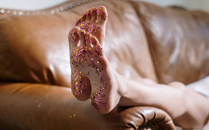 a imagem remete a uma criança que pulou carnaval em casa: são os pés com purpurina, de uma pessoa deitada em um sofá.