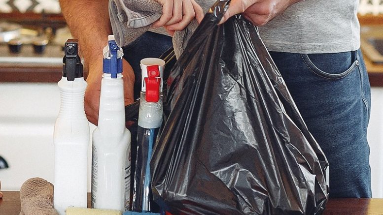 imagem de uma sacola preta plástica em que sao colocados produtos, a imagem é aproximada e mostra apenas as mão das pessoas.