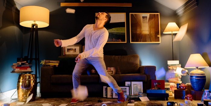 cena de Porta-retratos com dançarino Danilo Saccomori em uma sala, jogando papéis para cima