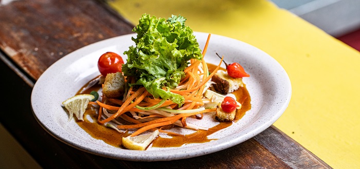 prato de salada do almoço de Páscoa com alface, tomaes cereja, cenoura ralada e molho escuro enfeitando o prato.