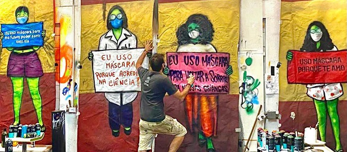 imagem do artista Mundano pintando paineis em lona de circo para a campanha #EuUsoMascaraPorque