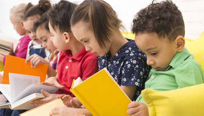 seis crianças lendo cada uma um livro infantil sentadas em um sofá,