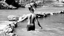 Foto de indio visto de costas, andando em um rio, exposta no festival que celebra o Dia do Índio,