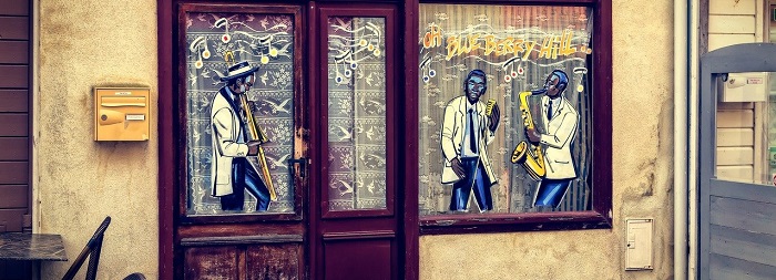 imagem da fachada de um clube de jazz com vidros pntados com musicos