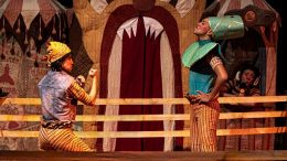 imagem de uma cena de um espetáculo cirsence com dois artistas vestidos de palhaço, em um ringue, simulanto uma luta