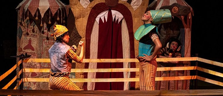 imagem de uma cena de um espetáculo cirsence com dois artistas vestidos de palhaço, em um ringue, simulanto uma luta