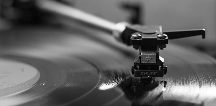 imagem de um toca discos de vinil, aparece o braço da vitrola, sobre um disco, em close