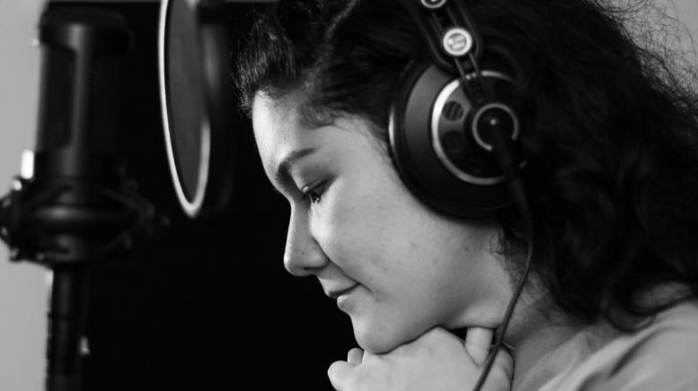 imagem em preto e branco da cantora Mariana Bisonti, vista de lado, em frente a um microfone de estúdio musical