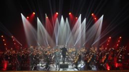 imagem da orquestra, com luzes de holofotes sobre ela.