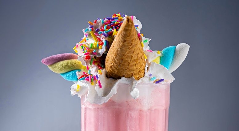 imagem da decoração de um milkshake de morando imitando unicórnio, com um cone de casquinha como chifre, marshmellows torcidos em coloridos como orelhas e chantilly com confeitos.