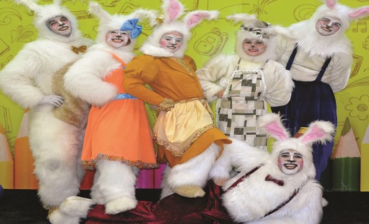 foto de 6 artistas vestidos de coelhinho da Pàscoa, um deles esta deitado no chao e os outros com uma das 'patinhas' apoiadas sobre eles. Todos sorreiem.