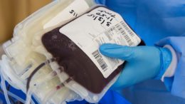 imagem de bolsas de sangue seguras por mãos com luvas azusi