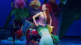 cena de A Pequena Sereia com Ariel sentada ainda no fundo do mar, sorrindo