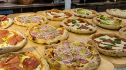 mesa de madeira sem toalha com várias pizzas colocadas sobre ela.