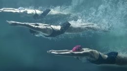 imagem de três nadadoras, embaixo dágua, iniciando a competição de nado.