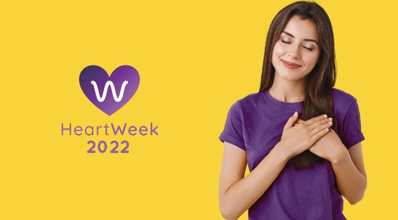 logo da heartweek e uma moça de olhos fechados sorrindo com a mão no coração. tudo isso em fundo amarelo ovo.