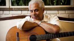 paulinho da Viola com os braços cruzados apoiados no violão