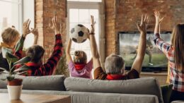 Excited, happy big family team watch sport match together on the couch at home