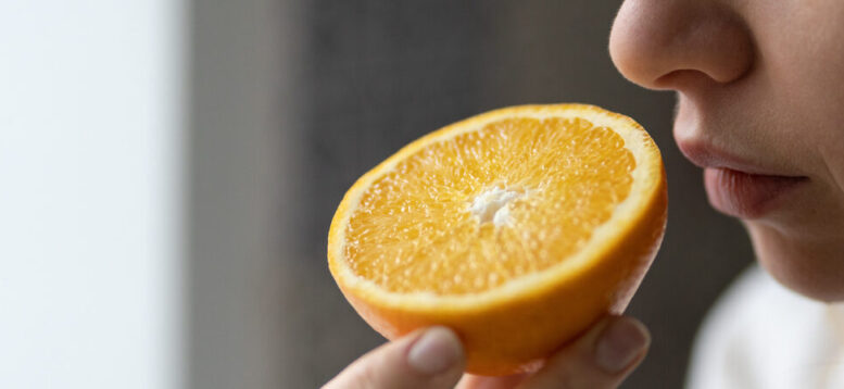 imagem em close de uma pessoa cheirando uma metade de laranja