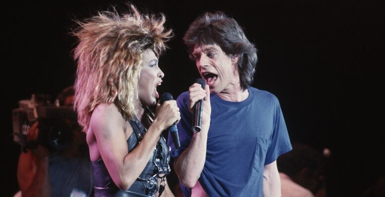 Imagem de show em 1985 com Tina Turner e Mick Jagger cantando no palco,