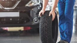 technician-with-blue-workwear-holding-wrench-tire-while-showing-thumb-up