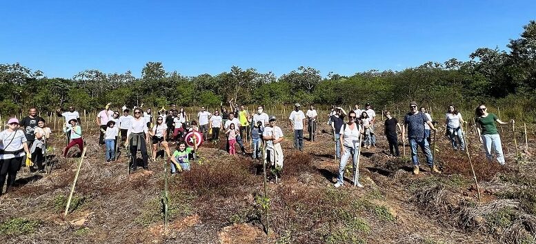 grupo de pessoas posa com picaretas em uma área descampada de um parque, é dia, o ceu está azul sem núvens e faz sol.