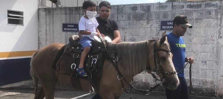 garotinho hospitalizado vai para a área externa do hospital andar a cavalo