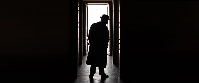 imagem de homem de chapéu no escuro olhando em um corredor