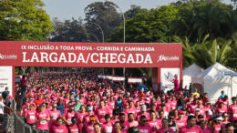 imagem da largada com centenas de pessoas de camiseta rosa passando embaixo do portal com os dizeres Laragada/Chegada