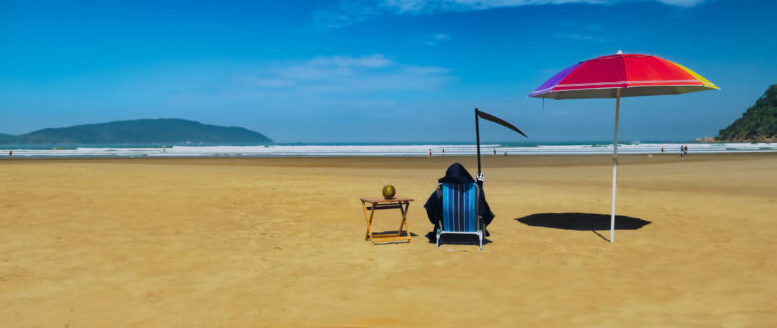cena de uma praia quase vazia com a 'morte e sua foice sentada em uma cadeira de rpaia com uma mesinha e um coco verde em cima, além de um guarda-sol
