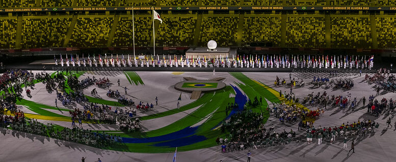 imagem de um estádio olímpico a partir de uma arquibancada, durante o desfile da delegação brsileira na abertura dos jogos paralimpicos de toquio.