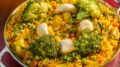 prato de paella vegetariana com cogumelos, brocoli e arroz de açafrão, em uma baixela de alumínio