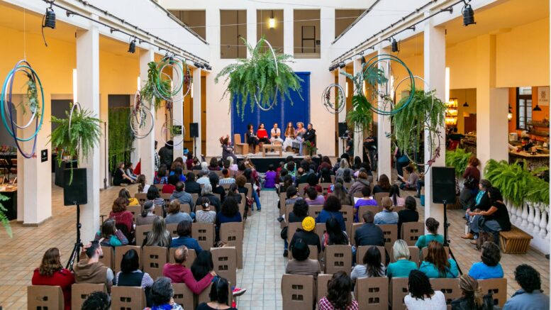 imagem de um hall com muitas cadeiras posicionadas como publico voltadas a uma mesa no fundo com apresentadores, na ediçãõi 2018 do evento