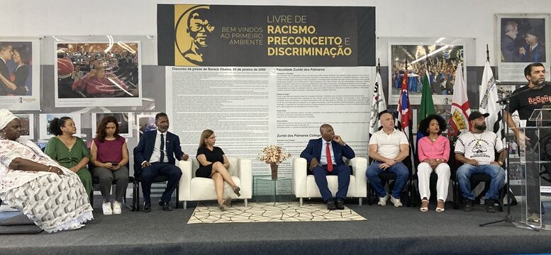 convidados sentados em um pequeno palco para a Cerimônia de lançamento do Colégio Técnico Dandara dos Palmares