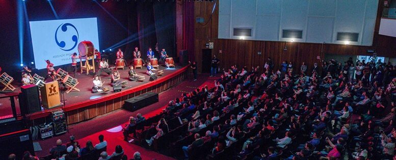 imagem de um auditório com platéia lotada e tambores japoneses no palco